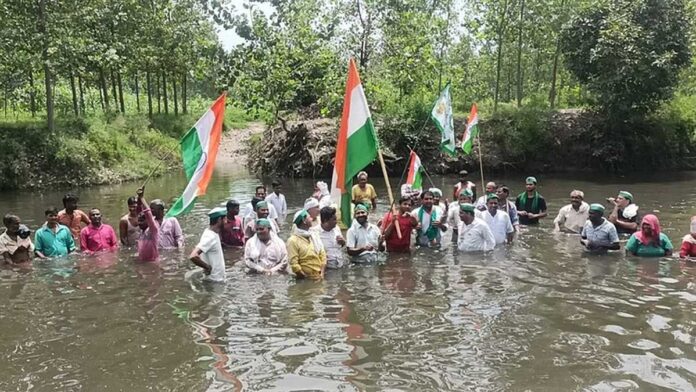 किसानों ने पानी में उतरकर किया ध्वजारोहण, हिंडन नदी पर पुल न‍िर्माण कराने की मांग